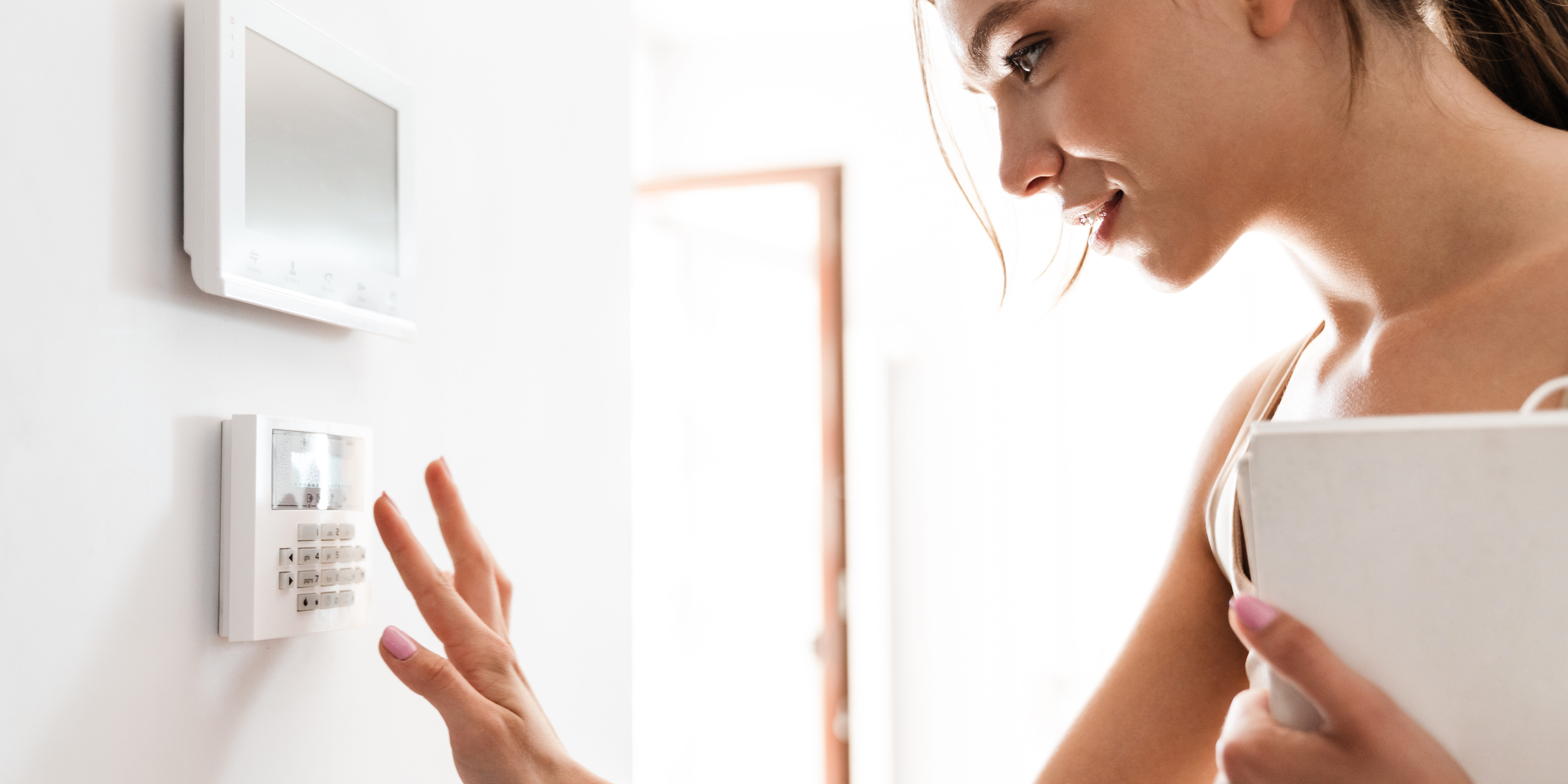 Young woman entering code on keypad of home security alarm