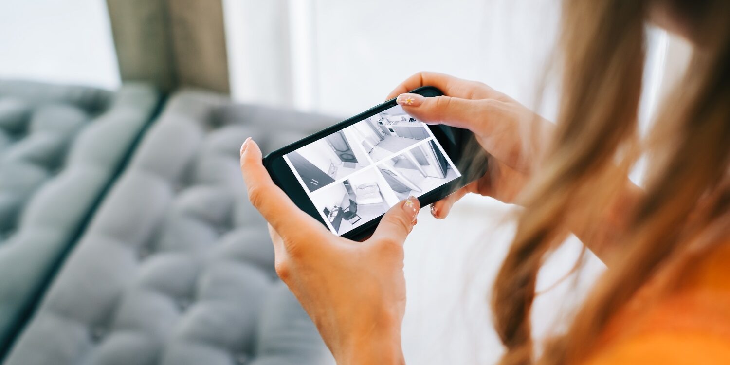 Caucasian woman monitoring security cameras on smartphone indoors, closeup.