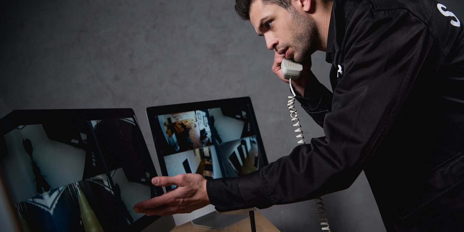guard talking on telephone and looking at computer monitor