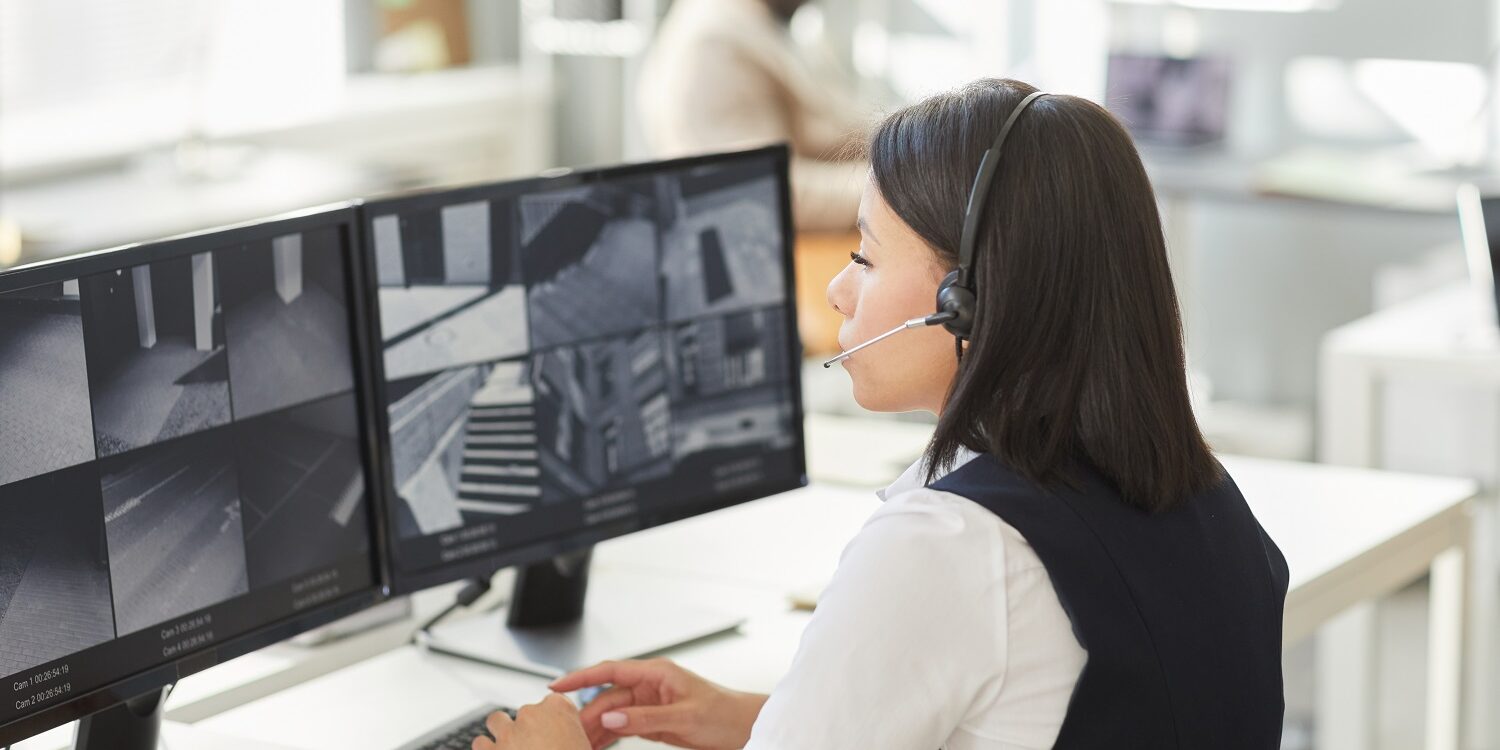 Young woman looking at surveillance camera feeds in security office