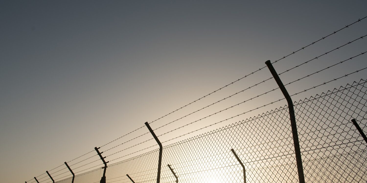 Bright sun behind security fence