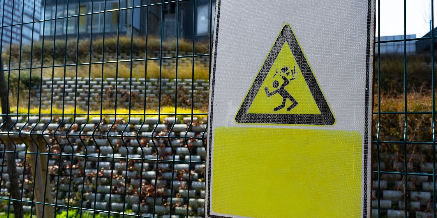 Yellow electric safety sign outside on metal gate