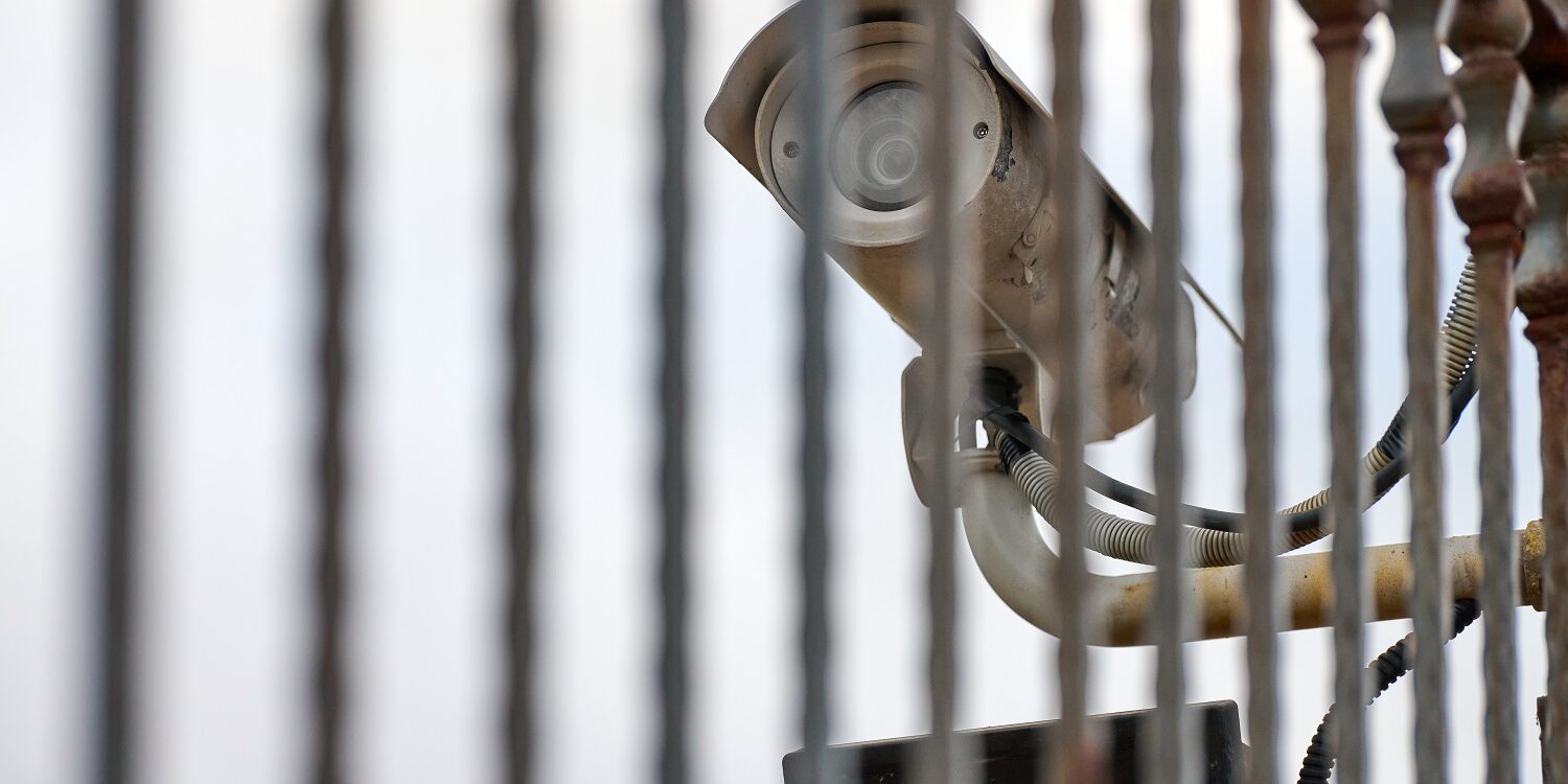 IP CCTV security camera and iron fence, urban cityscape